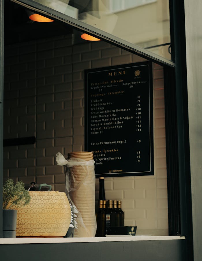 A warm cafe window features a displayed menu alongside inviting decor items, creating a cozy atmosphere.